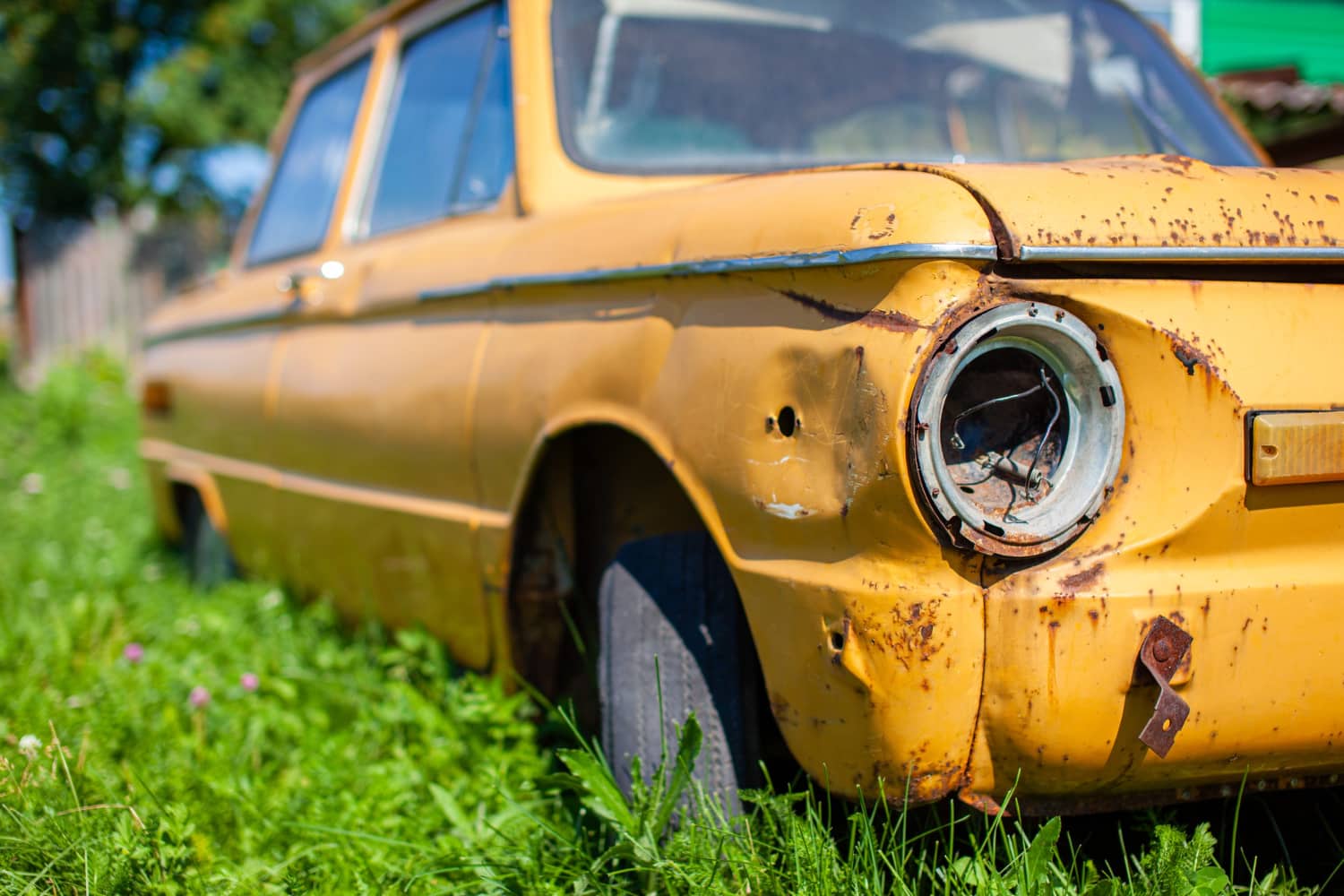 Rusty, damaged wagon parked in tall grass