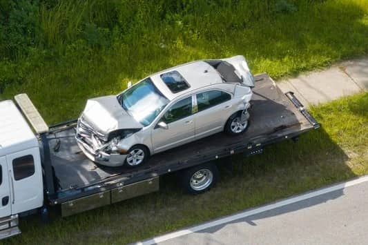 Aerial view of a junk car loaded on a flatbed tow truck