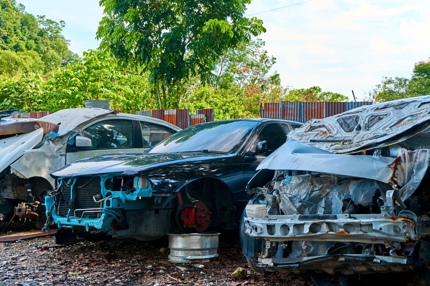 Several wrecked cars parked together in a junkyard