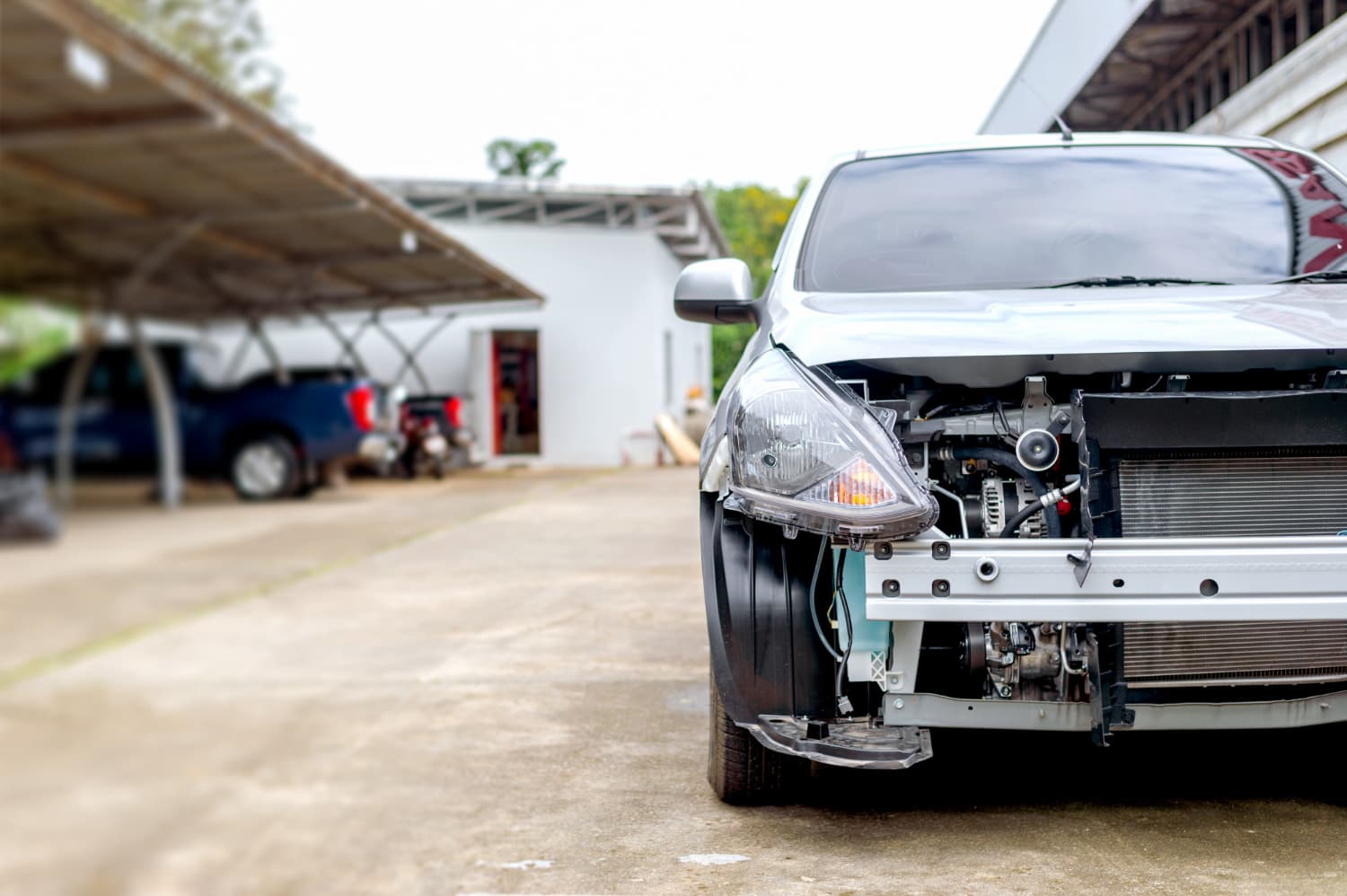 Car with an exposed, disassembled engine bay in a driveway