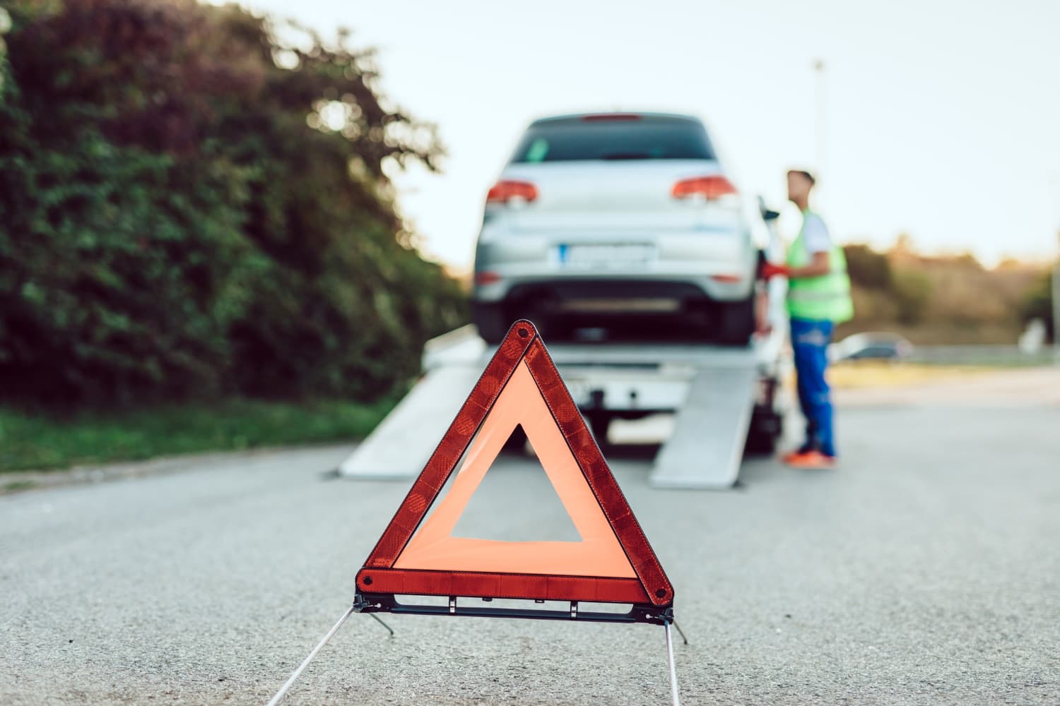 Loading a vehicle onto a flatbed with a roadside warning triangle set out