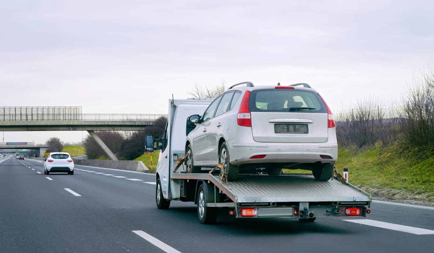 Flatbed tow truck hauling a station wagon on the highway
