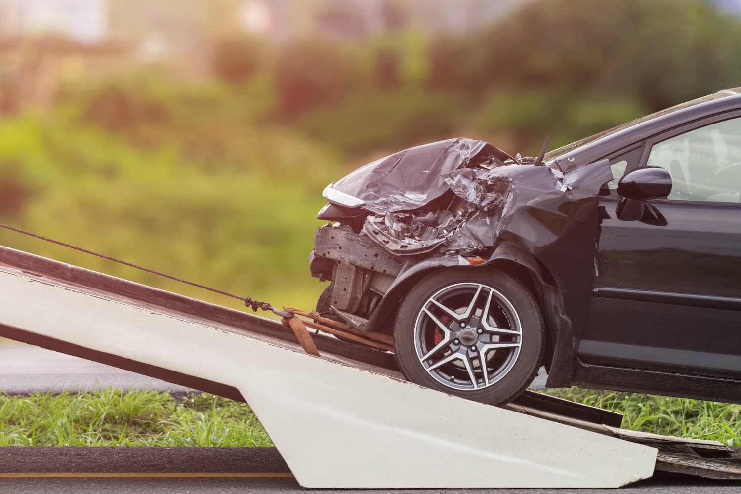 Car with severe front-end crash damage on a tow ramp